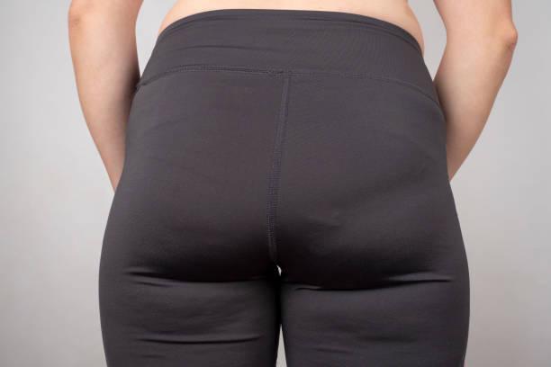 overweight female buttocks in black leggings closeup.